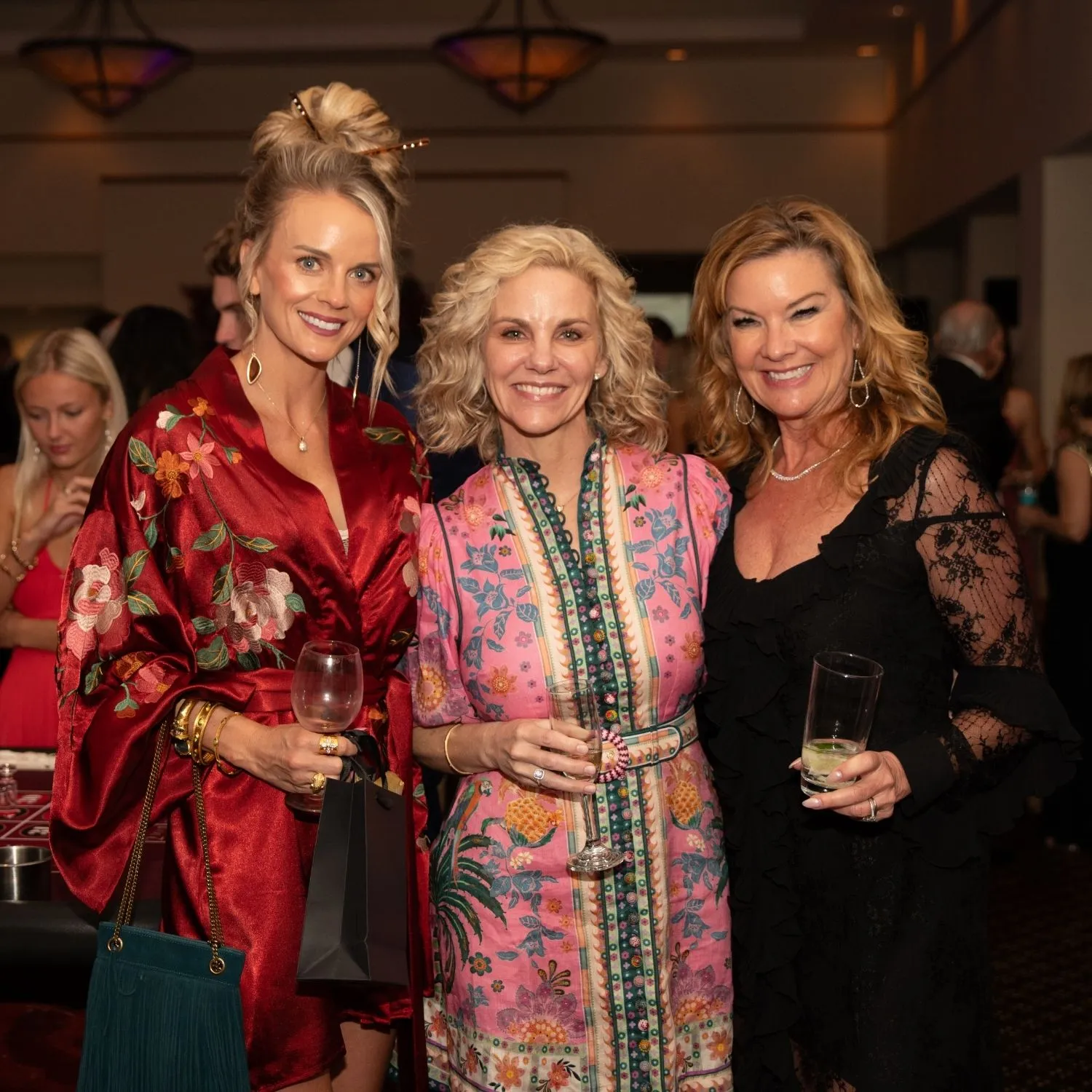 Three guests smiling together with drinks in hand