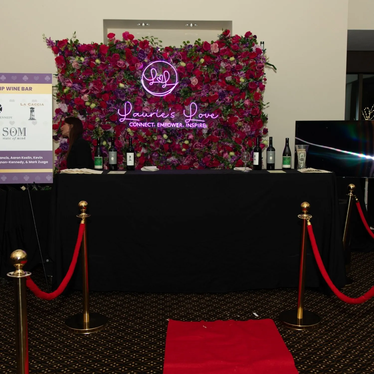 The wine bar in front of a rose wall with the Laurie’s Love neon sign