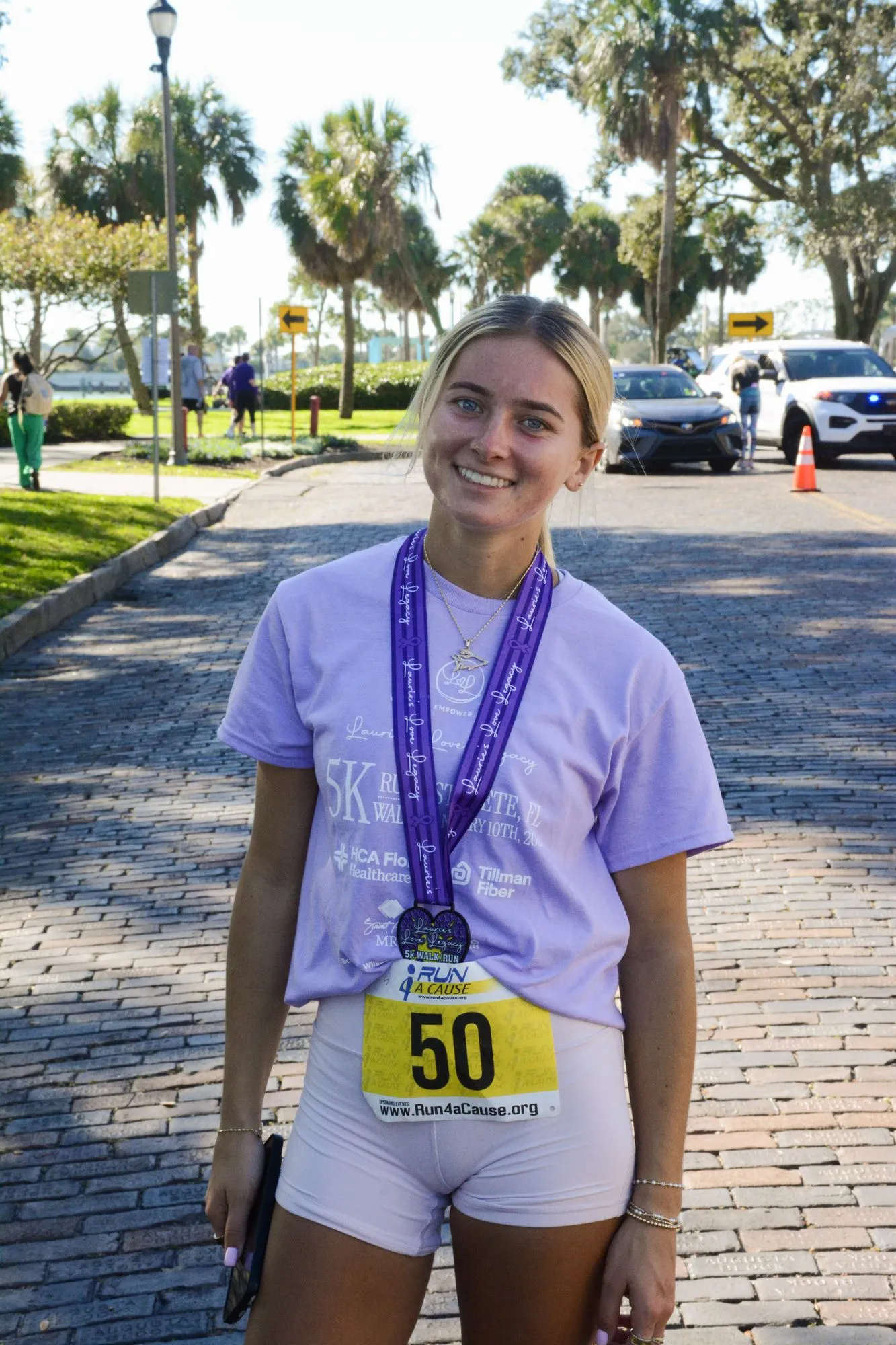 A young woman smiles with her finisher medal after the 2026 Legacy Run