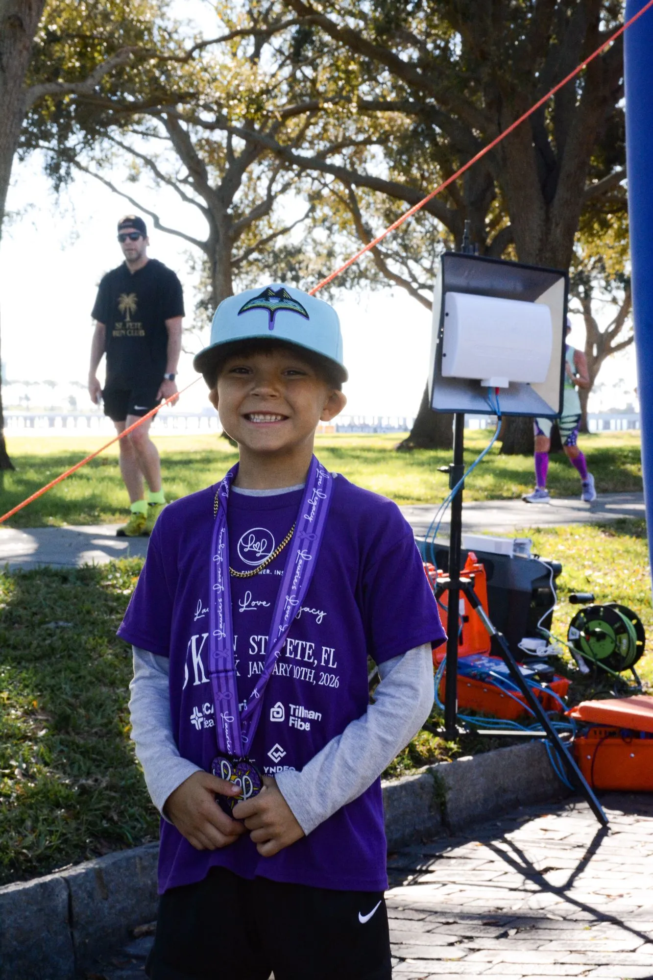 A child in a purple Laurie’s Love shirt shows off a finisher medal at the 2026 Legacy Run