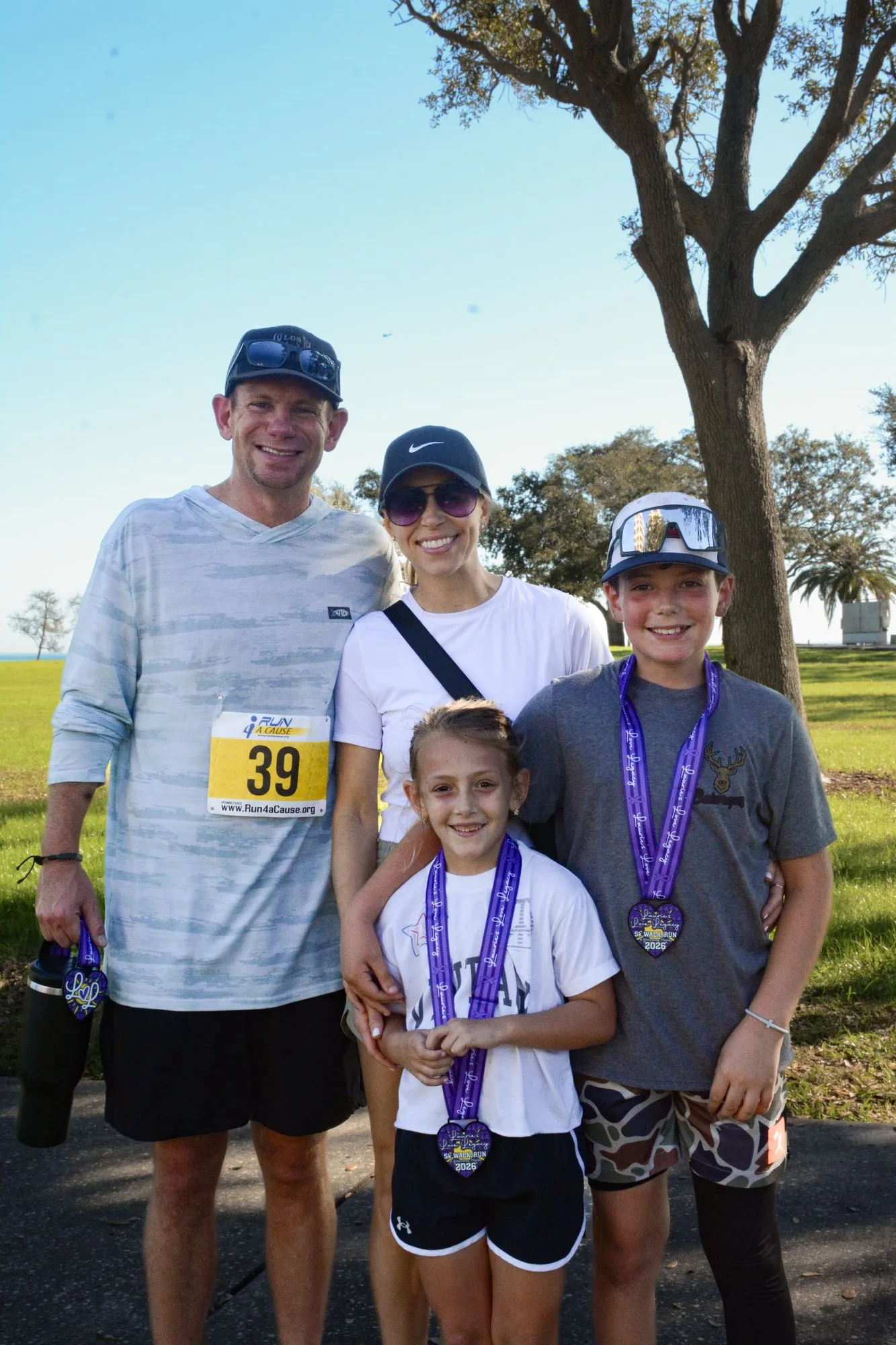 A family with young kids wearing race bibs and medals at the 2026 Legacy Run
