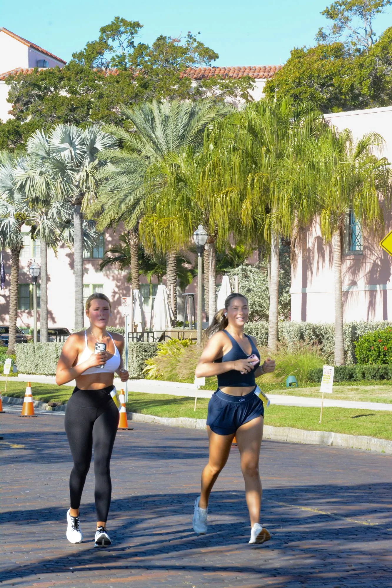 Two runners side by side on a palm-lined street during the 2026 Legacy Run