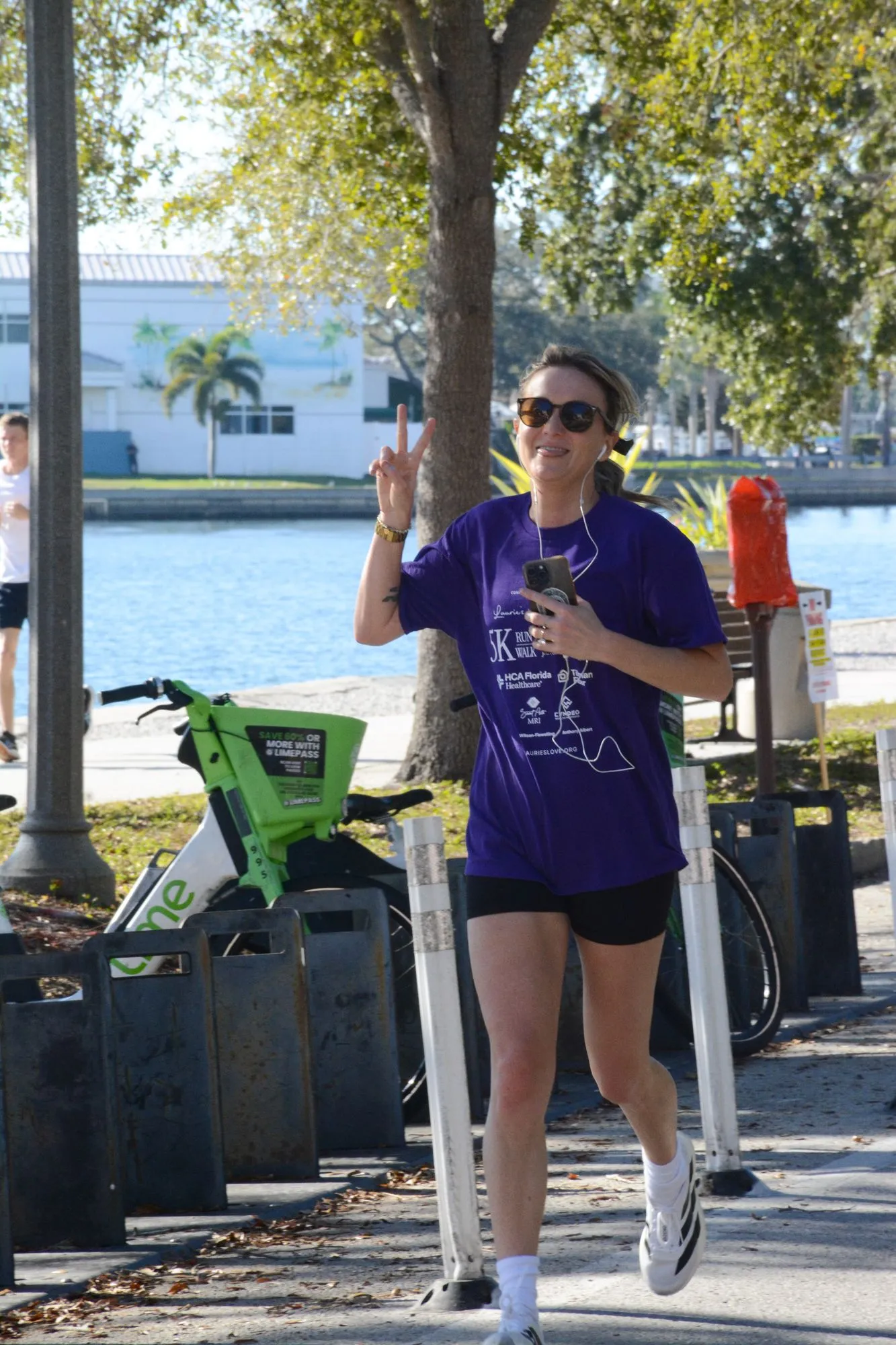 A runner in a purple Laurie’s Love shirt waves on the 2026 course
